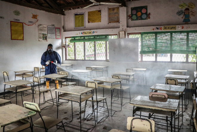 Gesundheitspersonal sprüht Desinfektionsmittel in einer leeren Schule in Gampaha