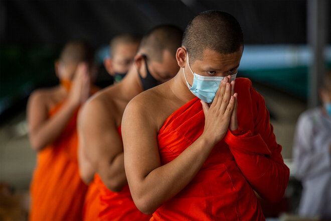 Thailändische Mönche sprechen ein Gebet, während sie Gesichtsmasken tragen